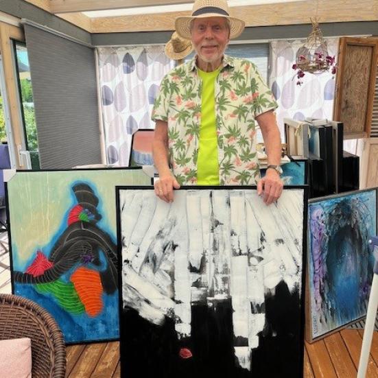 John Elsfort med tre af sine malerier